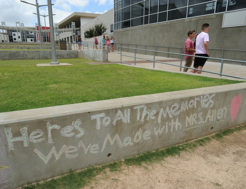 Heritage High School student decorate a wall and walkway between the school and arena Tuesday in Rogers after reports of teacher Linda Woods Allen was killed in Florida.