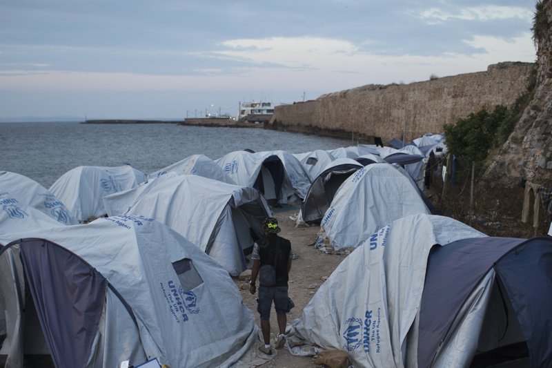 A migrant from Morocco walks among tents at a beach outside the Souda refugee camp in front of a stone wall of the castle of Chios island, Greece, Friday, June 9, 2017. The International Organization for Migration says more than 60,000 migrants have reached the shores of Europe so far in 2017, a sizable decrease compared to the same period last year. (AP Photo/Petros Giannakouris)