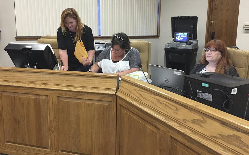 NWA Democrat-Gazette/ALEX NICOLL Jennifer Price (left), Washington County Election Commission coordinator, and members Tonya Bryant (center) and Debbie Corley process and canvass Farmington ballots Tuesday night at the Washington County Courthouse in Fayetteville.