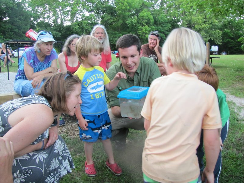 NWA DEMOCRAT-GAZETTE/Laurinda Joenks Sim Barrow, communications and development coordinator for the Northwest Arkansas Land Trust, shows a frog he caught in Lake Leatherwood to children gathered for a listening party of the FrogWatch USA Northwest Arkansas chapter.