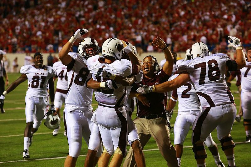 Louisiana-Monroe’s Kolton Browning (center) is mobbed by teammates and coaches after scoring the winning touchdown in the Warhawks’ upset victory over No. 8 Arkansas in 2012.