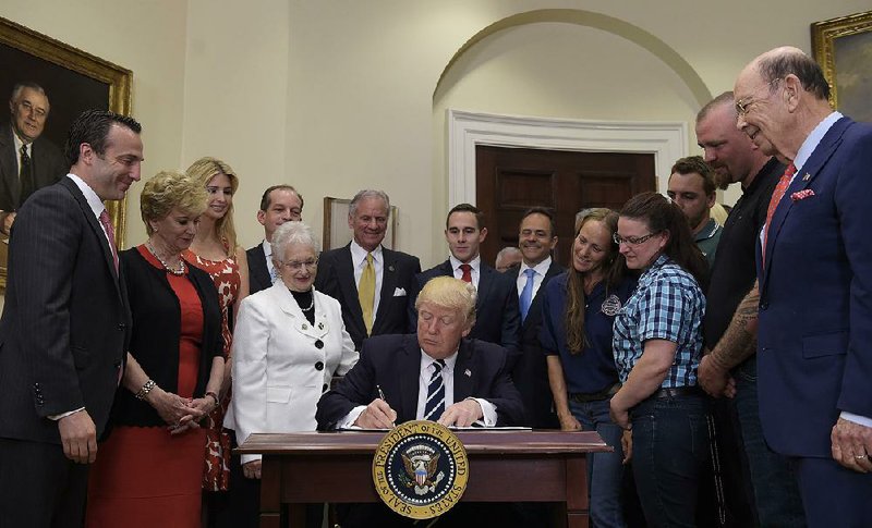 President Donald Trump signs his executive order Thursday to add funds for the ApprenticeshipUSA program.