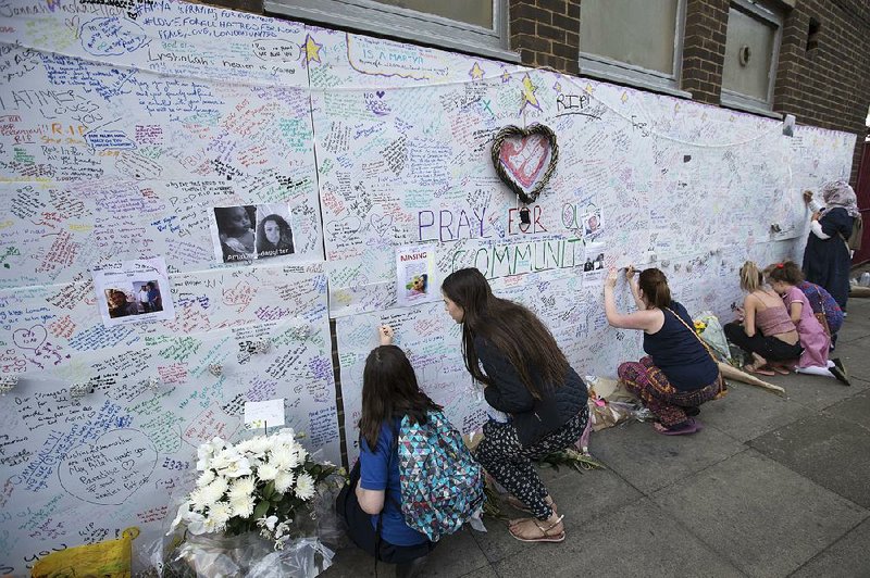 People write messages Thursday on a wall at the Latymer community center in London for the victims of the Grenfell Tower fire.
