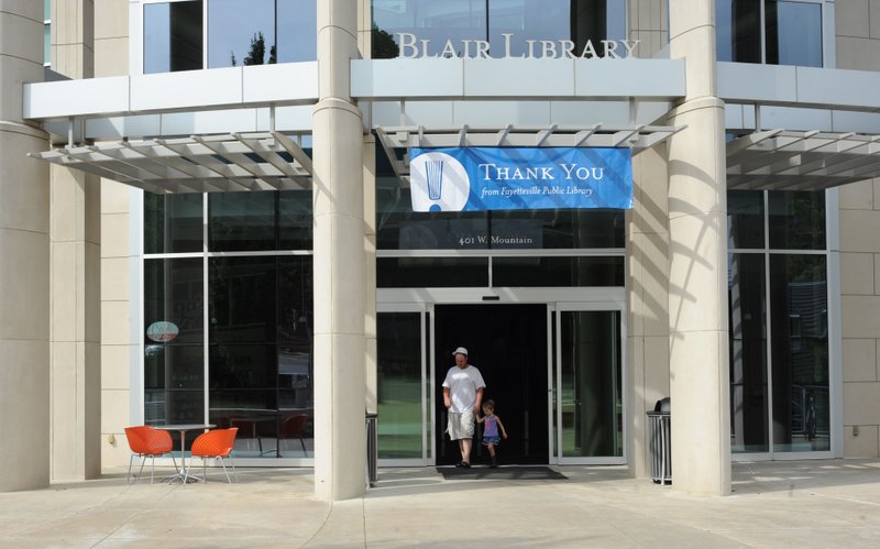 Patrons exit the Fayetteville Public Library Saturday, Aug. 13, 2016, beneath a sign thanking voters after a special election which raised the millage rate to support the library's operations and a planned expansion.