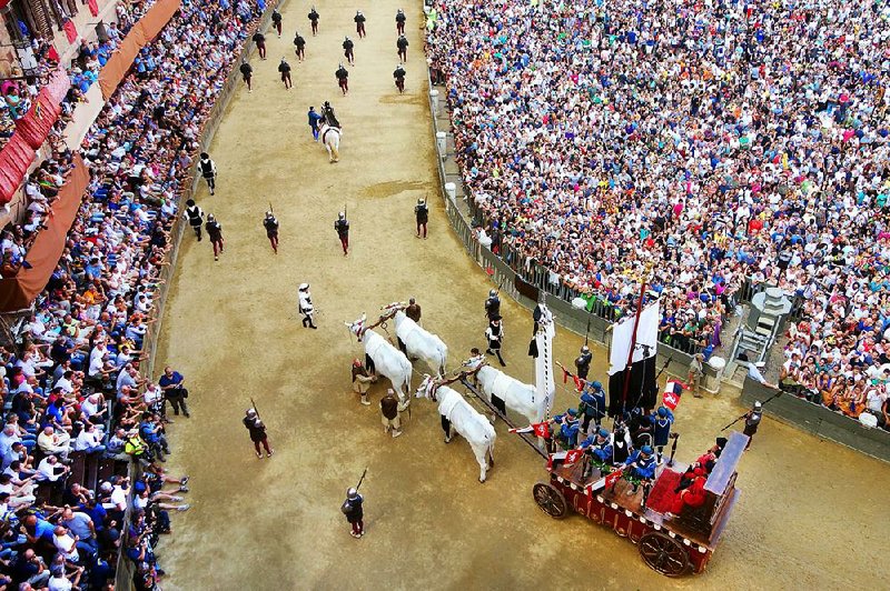 The crowd looks on as an oxen cart pulls the Palio banner through Siena’s main square.
