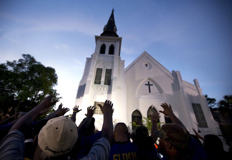 FILE -In this June 19, 2015 file photo, the men of Omega Psi Phi Fraternity Inc. lead a crowd of people in prayer outside the Emanuel AME Church, after a memorial for the nine people killed by Dylann Roof in Charleston, S.C. The pastor of the church is expected to announce the designer of a memorial to the nine people killed in the church's fellowship hall in a racist massacre two years ago Saturday, June 17, 2017. Other ceremonies are also planned to mark the second anniversary of the killings. (AP Photo/Stephen B. Morton, File)