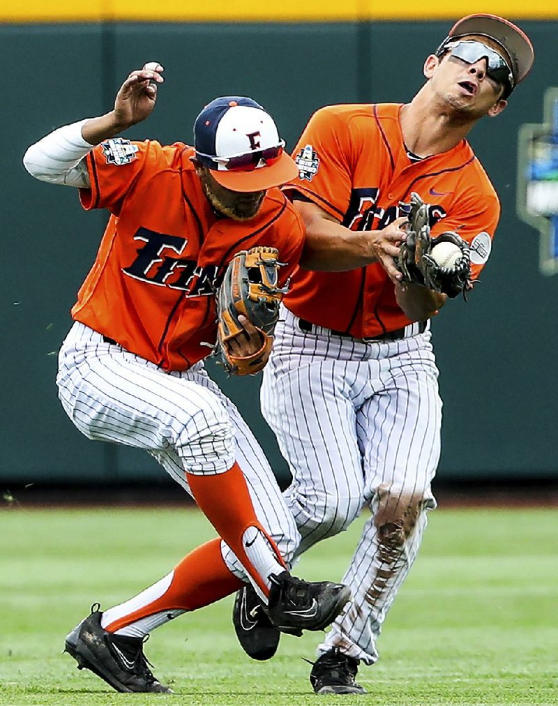 Cal State Fullerton’s Sahid Valenzuela (left) and Scott Hurst collide as Hurst makes the catch on a fly ball during Saturday’s opening game of the College World Series in Omaha, Neb. Oregon State won 6-5. 