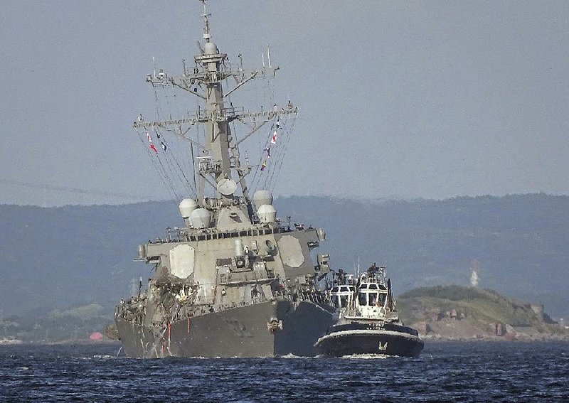 The USS Fitzgerald is towed to its home port of Yokosuka Naval Base south of Tokyo on Saturday. The destroyer’s collision with a cargo ship caused flooding in berthing areas as most of its crew slept.