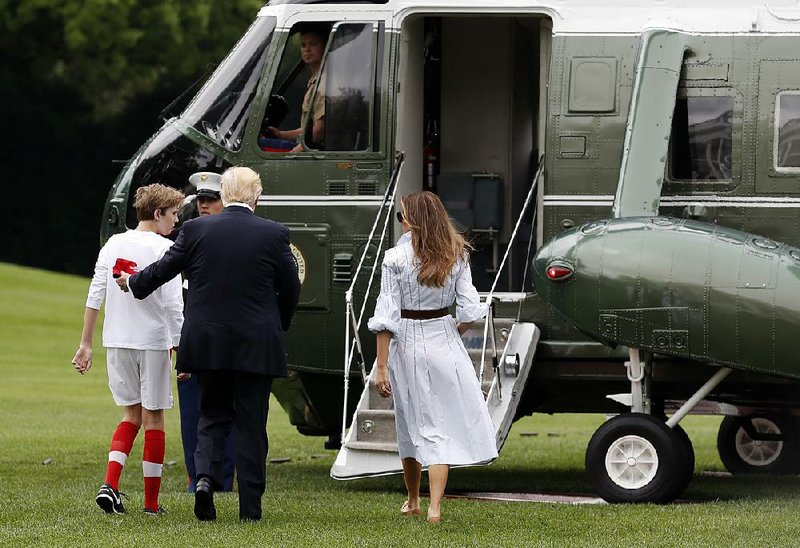 President Donald Trump boards Marine One with his son Barron and wife, Melania, on the White House lawn Saturday on his way to his first visit to the presidential retreat at Camp David.