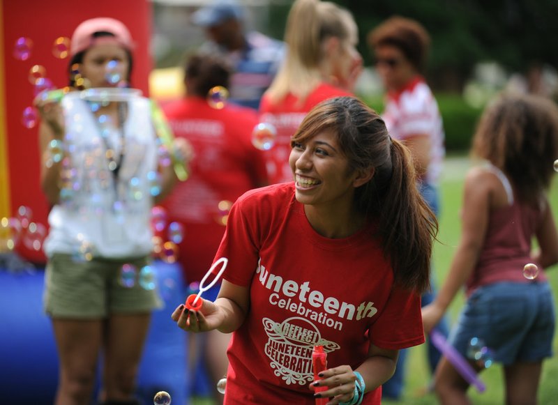 NWA Democrat-Gazette/ANDY SHUPE Daisy Mota, an incoming freshman at the University of Arkansas from Dallas, laughs Saturday while blowing soap bubbles during the Juneteenth celebration in The Gardens on the University of Arkansas campus in Fayetteville. Juneteenth marks the anniversary of the emancipation of slaves in the United States.