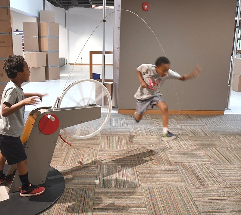 The Sentinel-Record/Mara Kuhn LASSO: Andruw Briggs, 6, cranks a wheel to spin a rope as Ernest Briggs, 7, jumps through it during Tinkerfest at Mid-America Science Museum on Saturday.