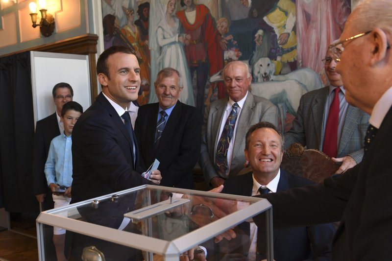 French President Emmanuel Macron, left, shakes hands wit a pooling station official after casting his ballot in the second round of the French parliamentary elections, in Le Touquet, northern France, Sunday, June 18, 2017. (Christophe Archambault/Pool Photo via AP)