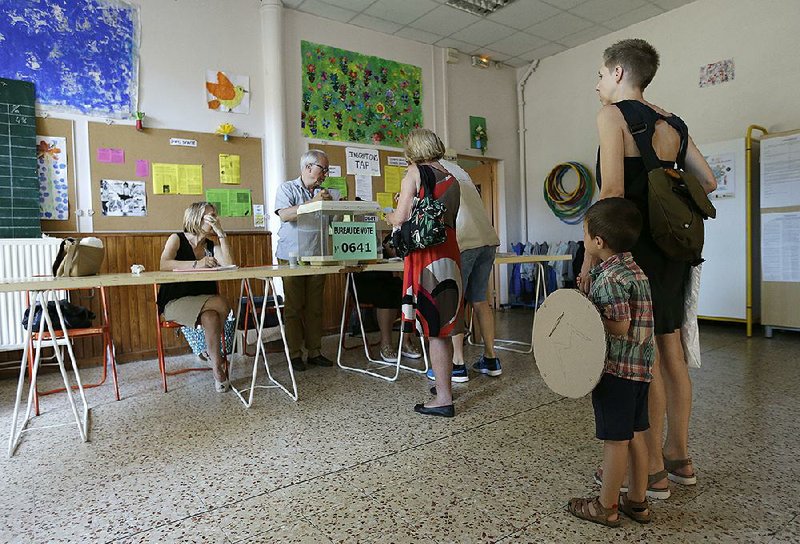 People wait to cast their ballots during the fi nal round of parliamentary elections at a polling station Sunday in Marseille, southern France.