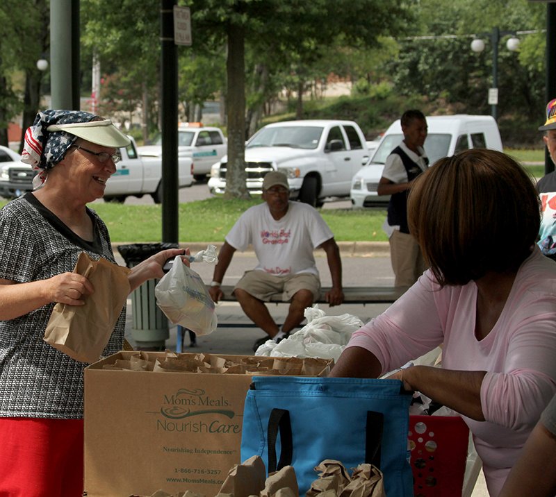 The Sentinel-Record/Max Bryan Karen Vincent, left, of Hot Springs, thanks Louise Brown, of World Mission Ministry, for food Saturday morning at the ministry's Sack Lunch Giveaway at Transportation Depot. The giveaway was held from 10 a.m. to 1 p.m. and provided lunch, clothing, household items and care packages to homeless and others.