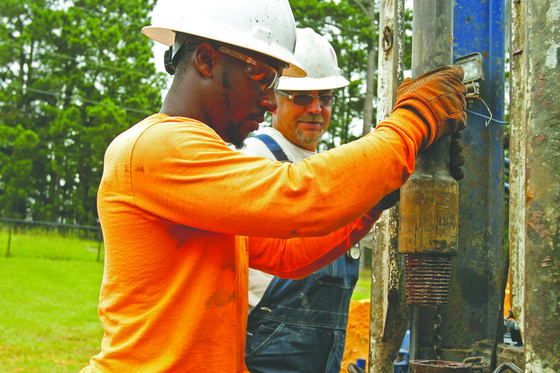 Drilling: Sid McIlverson watches as Ray Brown connects pipes to each other while drilling at the Arkansas 
Welcome Center. McIlverson and Brown are employees of Pender Water Wells of Texarkana contracted to construct a new real-time groundwater level monitoring well at the welcome center.