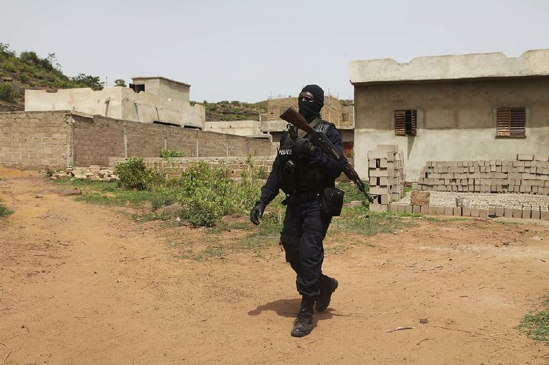 A Malian police officer patrols Monday outside Campement Kangaba, a tourist resort near Bamako that was the target of a militant group’s attack.