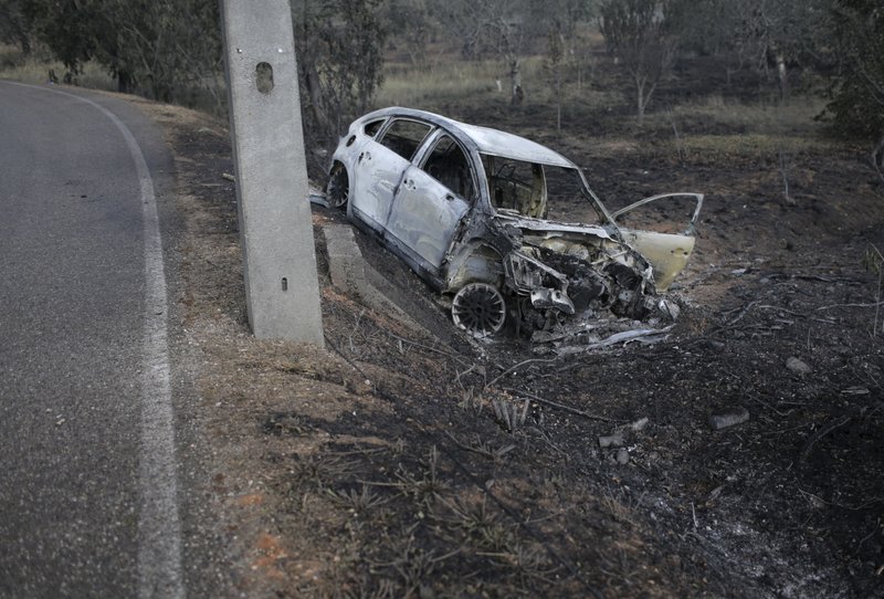 A burnt car lies where it went off the road in the village of Nodeirinho, near Pedrogao Grande, central Portugal, Monday, June 19 2017. At least 11 people were killed in the village Saturday when it was swept by a forest fire. Raging forest fires in central Portugal killed at least 62 people, many of them trapped in their cars as flames swept over roads Saturday evening. 