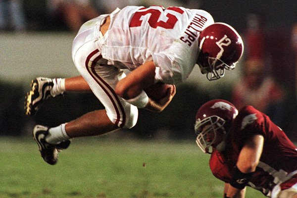 Alabama quarterback John David Phillips (12) is up-ended by Arkansas defensive tackle Melvin Bradley during the third quarter of the Southeastern Conference game in Fayetteville, Ark., on Saturday, Sept. 26, 1998. Arkansas beat No. 22 Alabama 42-6. (AP Photo/Beau Rogers)