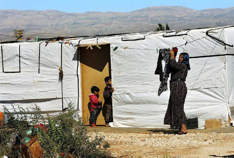 A Syrian woman hangs laundry outside her tent at a refugee camp in Baalbek, Lebanon, on Tuesday. United Nations officials announced Tuesday, on World Refugee Day, that the European Union had donated about $100 million to provide aid to displaced Syrians in Lebanon, Jordan and Turkey. 