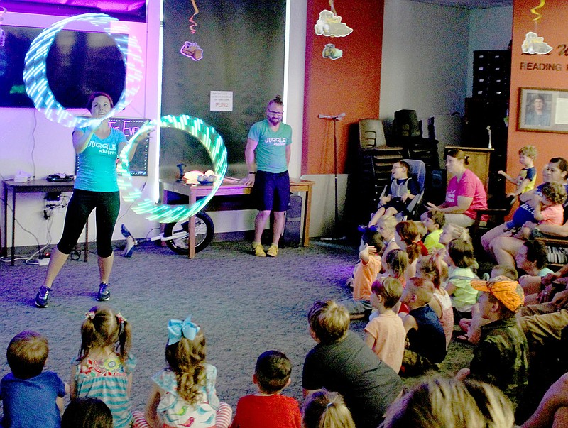 Keith Bryant/The Weekly Vista Kelsey Philo, left, twirls LED-illuminated hoops for a crowd that gathered at the Bella Vista Public Library for the Juggle Whatever show.