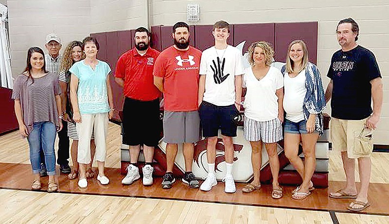MARK HUMPHREY ENTERPRISE-LEADER Bryce Means (in white T-shirt with hand print) a 2017 Lincoln graduate, celebrates signing a national letter of intent to play men&#8217;s college basketball for Bacone College, of Muskogee, Okla., at the Lincoln High School gym June 1. Joining Bryce (from left): Delaney McGee; Bryce&#8217;s grandfather, Leon Kimble; Bryce&#8217;s aunt, Mindy Babcock; Bryce&#8217;s grandmother, Reva Kimble; Bacone assistant men&#8217;s basketball coach, Stephen Hatfield; Lincoln assistant basketball coach, Austin Lewis; Bryce Means; Bryce&#8217;s mother, Tracy Means; Bryce&#8217;s sister, Cassie Robinson; and Lincoln head boys basketball coach Tim Rich.
