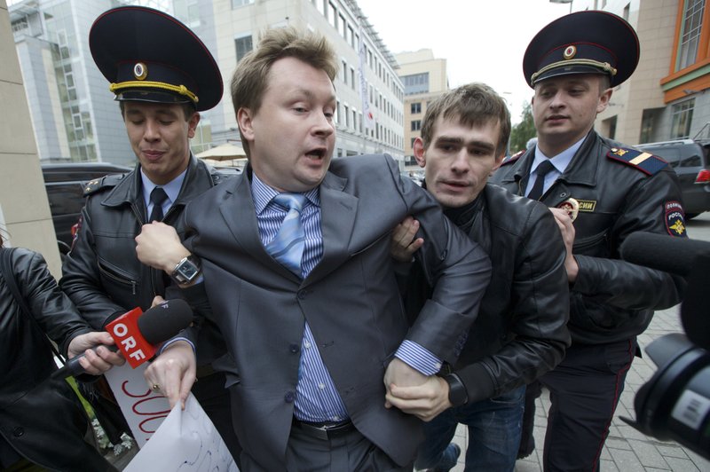 FILE - In this Sept. 25, 2013, file photo, police detain Russia's leading gay rights campaigner Nikolai Alexeyev, center, during a protest outside the Sochi 2014 Winter Olympic Games organizing committee office, in downtown Moscow, Russia. The European Court for Human Rights ruled on Tuesday, June 20, 2017, that Russia's law banning dissemination of so-called gay propaganda to minors violates the right to freedom of expression. (AP Photo/Ivan Sekretarev, File)