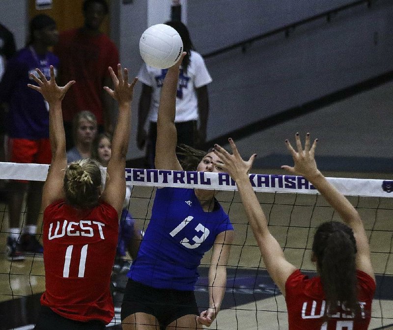 East All-Star Kennedy Sellers (center) of Nettleton spikes the ball between the West’s Klaire Trainor (left) of Springdale Har-Ber and Faith Waitsman of Fayetteville during Wednesday’s all-star volleyball game at the Farris Center in Conway. The West rallied from two sets down to knock off the East 3-2.