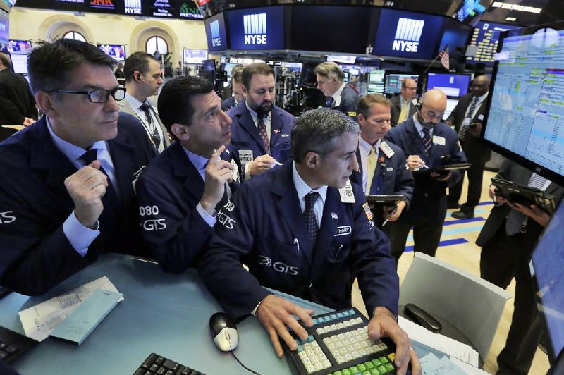 Specialists David Haubner (from left), Peter Mazza and Anthony Rinaldi work Wednesday on the floor of the New York Stock Exchange. U.S. stocks fell by the most in a month on Wednesday, retreating from all-time highs as crude oil slid into a bear market on concern a global supply glut will persist.