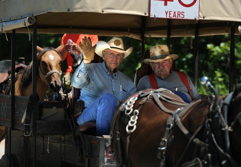 NWA Democrat-Gazette/ANDY SHUPE Brothers Jim (left) and George Parker ride Tuesday along Cedar Bluff Road in Washington County while participating in the John Henry Shaddox Memorial Wagon Train riding from Harrison to Springdale for the 73rd Rodeo of the Ozarks. Jim Parker is the wagon master of the train, and the two have led the wagon train in the front wagon for 25 years.
