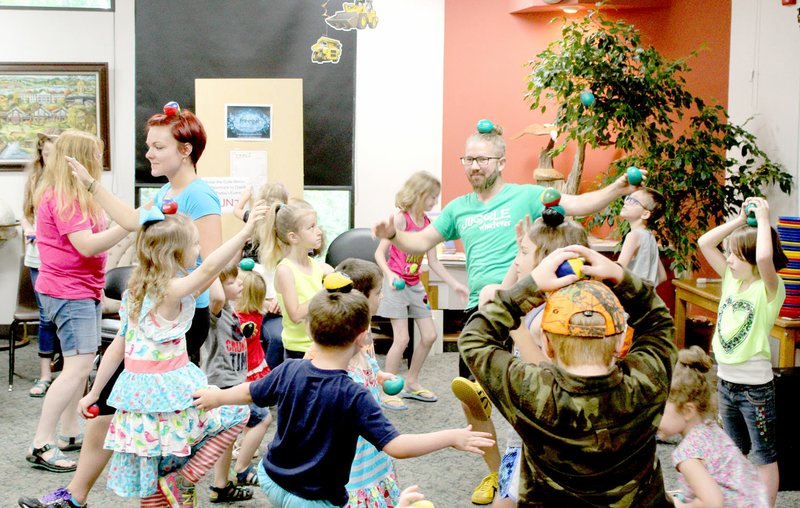 NWA Democrat-Gazette/KEITH BRYANT Kids in the audience practice their balance with Kelsey Philo and Jeremy Philo during the Juggle Whatever show at the Bella Vista Public Library.