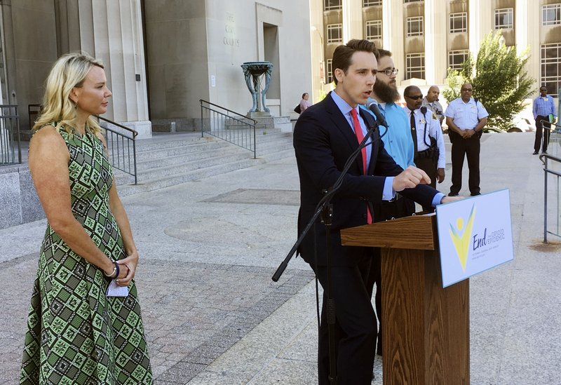 Missouri Attorney General Josh Hawley speaks at a news conference Wednesday, June 21, 2017, in St. Louis where announced he is suing three large pharmaceutical companies, saying their deceptive marketing practices contributed to an opioid abuse crisis in the state. Looking on at left is Jammie Fabick, whose 17-year-old daughter died of an opioid overdose in 2014. (AP Photo/Jim Salter)