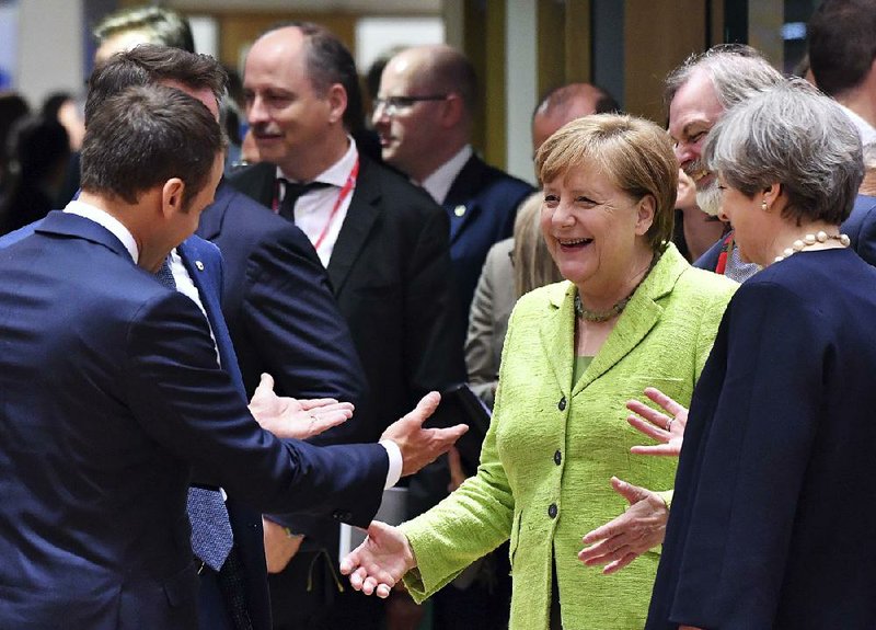 German Chancellor Angela Merkel (second right) speaks with French President Emmanuel Macron (left) and British Prime Minister Theresa May (right) during a roundtable meeting Thursday at an EU summit in Brussels.