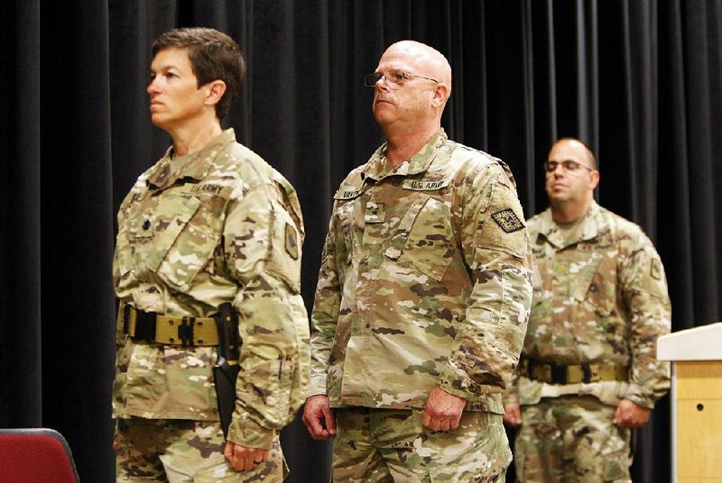 Lt. Col. Miriam Carlisle (left), Brig. Gen. Kirk Van Pelt and Maj. Shay Matyja, all with the Arkansas National Guard’s 39th Infantry Brigade, stand at attention for the national anthem during a deployment ceremony at Camp Robinson on Thursday in North Little Rock. More photos are available at arkansasonline.com/galleries.