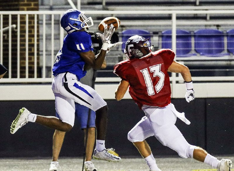 East wide receiver Marquis Pleasant (left) of Conway hauls in a pass behind West defensive back Tucker Hall of Foreman in the Arkansas High School Coaches Association All-Star football game Friday night. The East opened up a 35-point lead at halftime and cruised past the West 55-14.