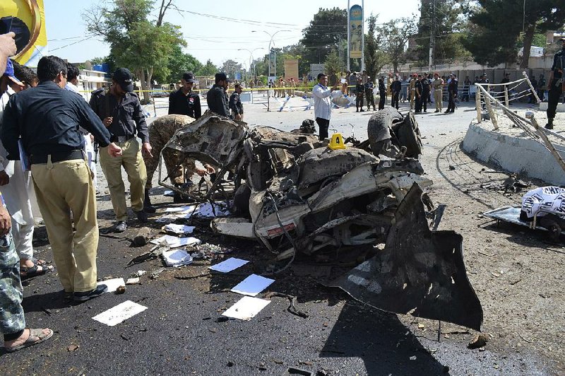 Police officers examine the debris after an explosion Friday in Quetta, Pakistan.