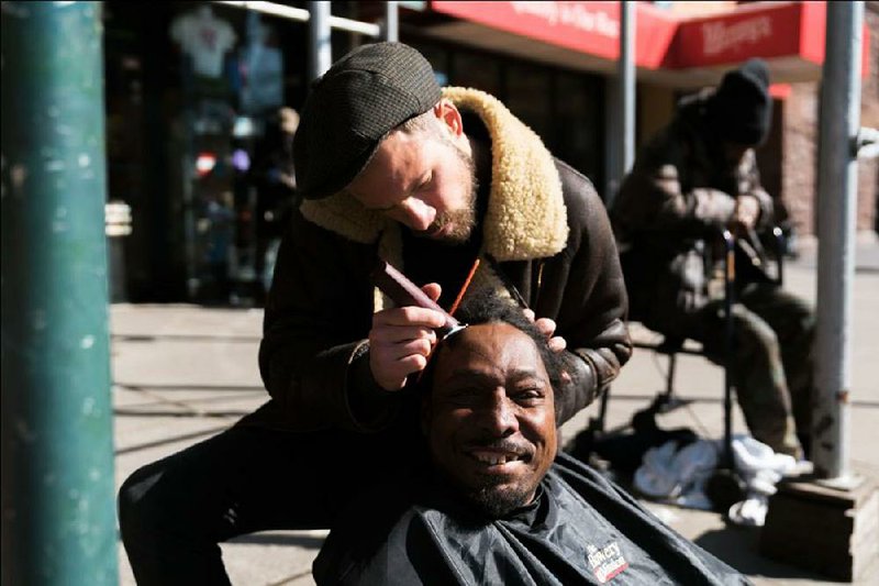 Joshua Coombes, a hairdresser and founder of #DoSomething-ForNothing, cuts the hair of a homeless man in Harlem, N.Y., in February.  