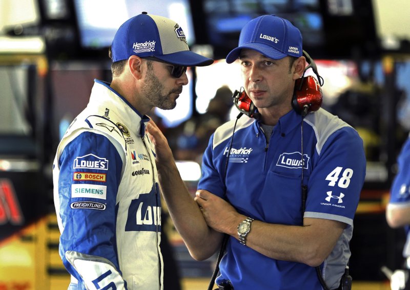 FILE - In this Feb. 12, 2016, file photo, Jimmie Johnson, left, talks with crew chief Chad Knaus in the garage during a practice session for a NASCAR auto race at Daytona International Speedway, in Daytona Beach, Fla. (AP Photo/Terry Renna, File)