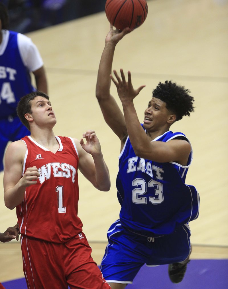 East guard Marquis Eaton (right) of Jonesboro puts a shot up over West defender Matthew Wilson of Farmington in Thursday’s Arkansas High School Coaches Association All-Star boys basketball game at the Farris Center in Conway. Eaton had 11 points, but the West rallied from an early deficit to beat the East 110-98. 
