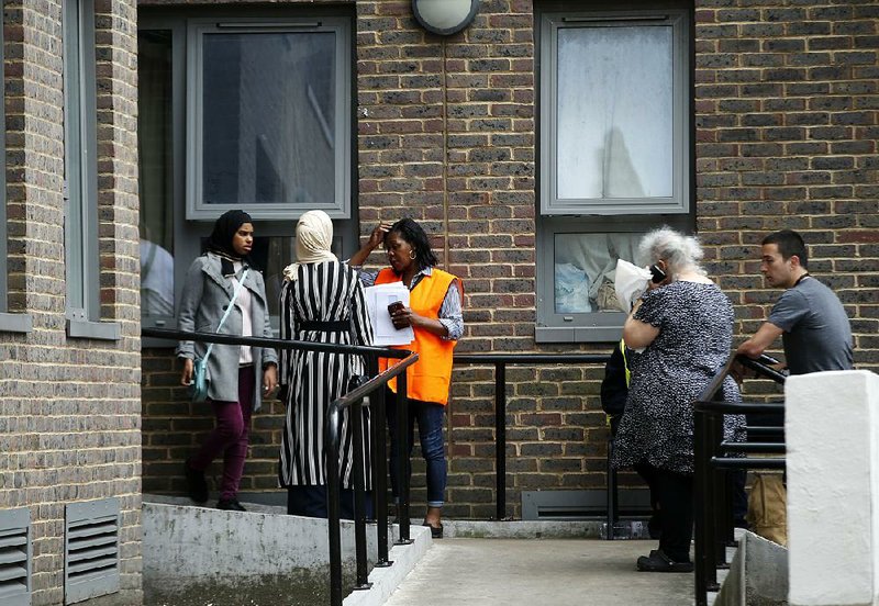 People gather Saturday outside the Dorney block in London’s Chalcots Estate neighborhood as officials evacuate four public housing towers so that fire prevention measures could be undertaken.