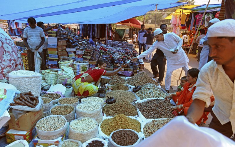 In this June 16, 2017 photo, Indians buy dry fruits from a roadside vendor at a market in New Delhi, India. Indian businesses are in a tizzy trying to comply with a long-awaited reform in the country&#x2019;s sales regime. The government says the Goods and Services Tax going into effect July 1 will boost the economy by streamlining business within a single market. Traders and business owners are still trying to figure out how it will work. (AP Photo/Altaf Qadri)