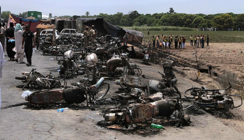 Pakistan army soldiers stands guard while rescue workers examine the site of an oil tanker explosion at a highway near Bahawalpur, Pakistan, on Sunday, June 25, 2017.