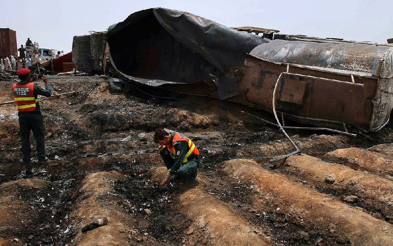 Pakistani rescue workers examine the site of an oil-tanker explosion on a highway Sunday near Bahawalpur, Pakistan.