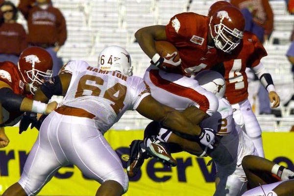 Arkansas running back Cedric Cobbs jumps over Texas defenders Casey Hampton (64) and Montrell Flowers in the 2000 Cotton Bowl, a 27-6 Razorbacks’ victory.