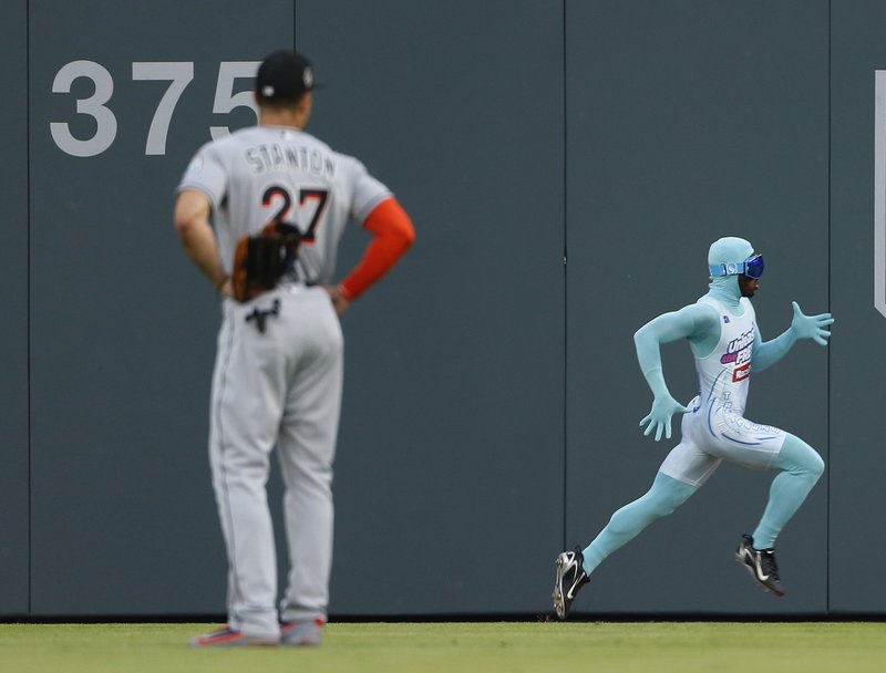 Atlanta Braves grounds crew member and former college track star Nigel Talton runs past Miami Marlins right fielder Giancarlo Stanton (27) as he races a fan from the left field corner to the right field corner during Atlanta Braves "Beat The Freeze" promotion during a baseball game against the Miami Marlins Friday, June 16, 2017, in Atlanta. 