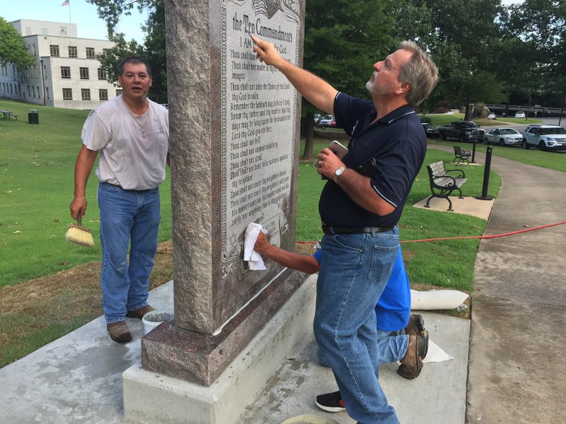 Employees from Wilbert Memorials put finishing touches on the Ten Commandments statue on state Capitol grounds Tuesday morning.