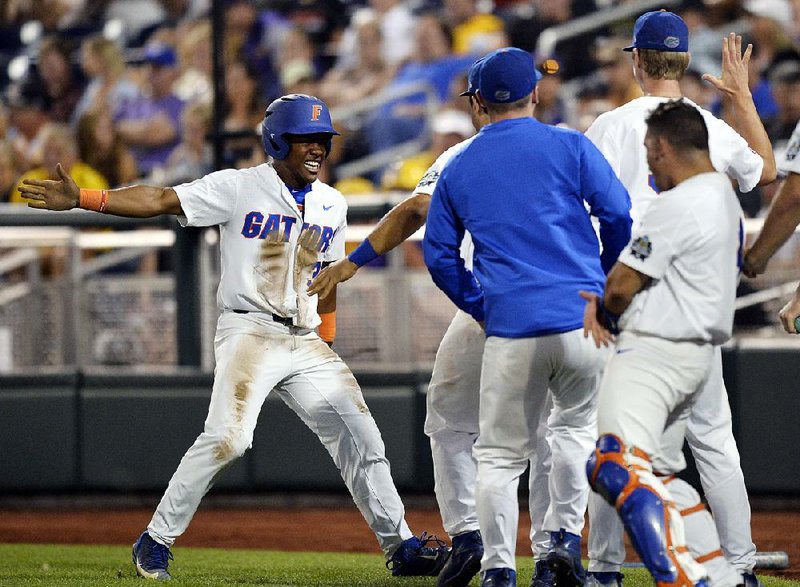 Florida’s Andrew Baker is congratulated by teammates after scoring a run in the eighth inning on a hit batter Tuesday night in Game 2 of the College World Series championship series at Omaha, Neb. The Gators won 6-1 to claim their first national title.