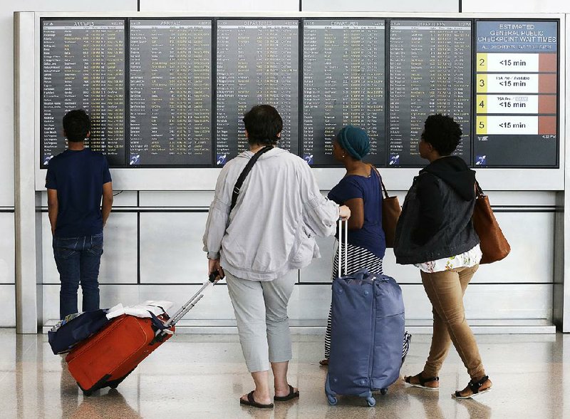 Travelers check arrival and departure information Monday at Seattle-Tacoma International Airport in Washington state. Government lawyers were working Tuesday on guidelines to enforce a travel ban on citizens from six mostly Muslim countries. 