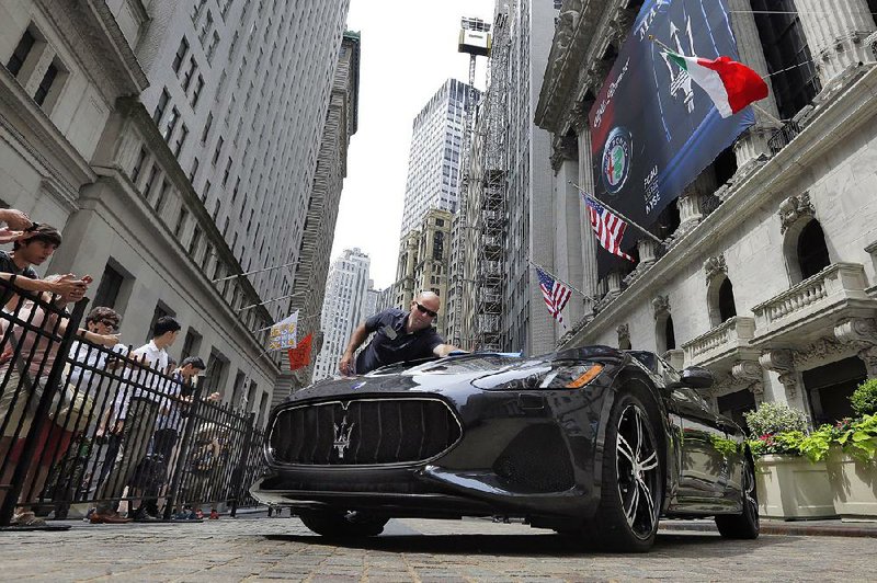 A worker from Fiat Chrysler Automobiles cleans a Maserati GranTurismo MC displayed Tuesday in front of the New York Stock Exchange.