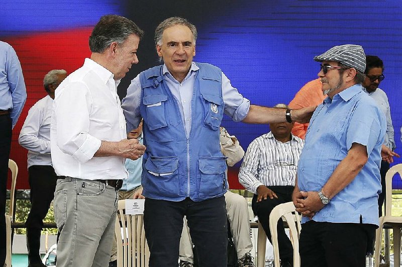 Jean Arnault (center), U.N. representative for the Colombian peace process, talks to Colombian President Juan Manuel Santos (left), and Rodrigo Londono, the commander of the Revolutionary Armed Forces of Colombia, during a ceremony Tuesday in Buenavista, Colombia.
