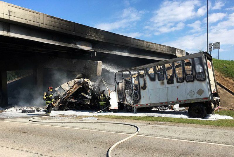 Jonesboro firefighters stand by after a tractor-trailer crashed into an overpass beam on Interstate 555 near Jonesboro on Tuesday in the photo from the Jonesboro Police Department. The highway officials are assessing the damage from the resulting fire to determine the overpass’ structural soundness. More photos are available at arkansasonline.com/galleries.